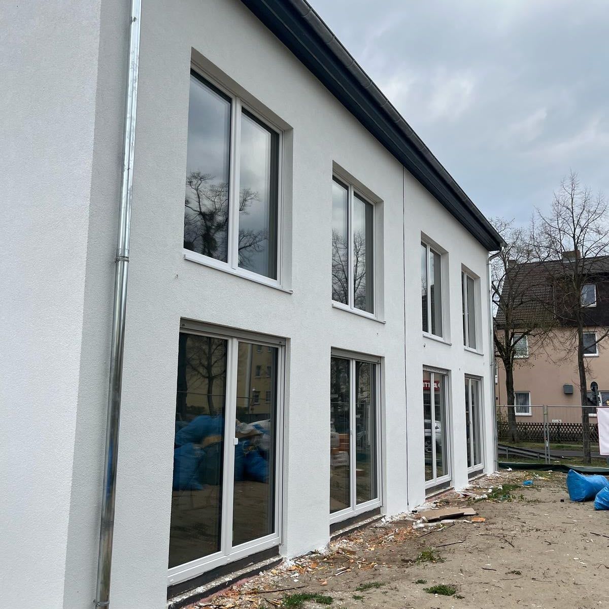 Neubau mit heller Putzfassade und großen bodentiefen Fenstern